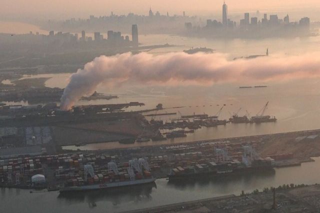The fire's smoke edges into the harbor